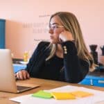 woman in black long sleeve shirt wearing black framed eyeglasses using macbook