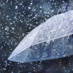 Transparent umbrella under heavy rain against water drops splash background. Rainy weather concept.