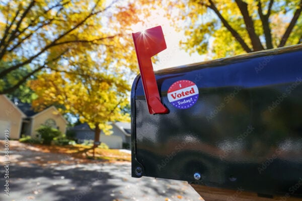 Mailbox with an "I voted today" sticker on it with sun flare behind flag, absentee voting through the mail