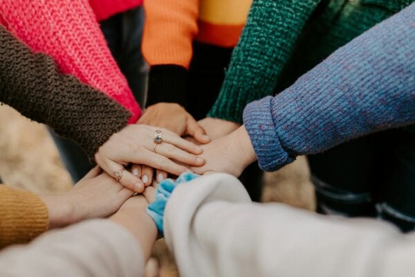 Community members stack their hands together