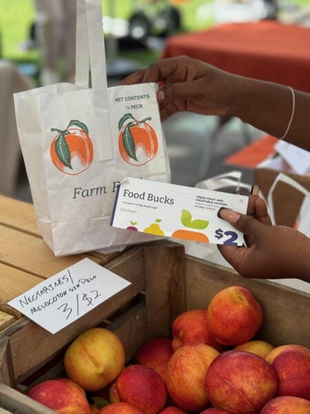 A shopper uses a PA Food Bucks voucher to buy fresh produce