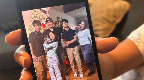 Wendys Martinez shows a photo of her and her husband, Carlos Moreno, with their family.