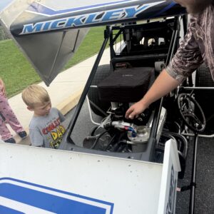 Upper Adams Intermediate School student examines a race car engine with Brayden Mickley