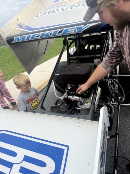 Upper Adams Intermediate School student examines a race car engine with Brayden Mickley